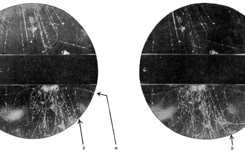 Particles (white lines) in a cloud chamber with a lead bar (black) across the centre. 2 lines that form an upside-down āVā whose vertex is below the lead bar show the new strange particle.